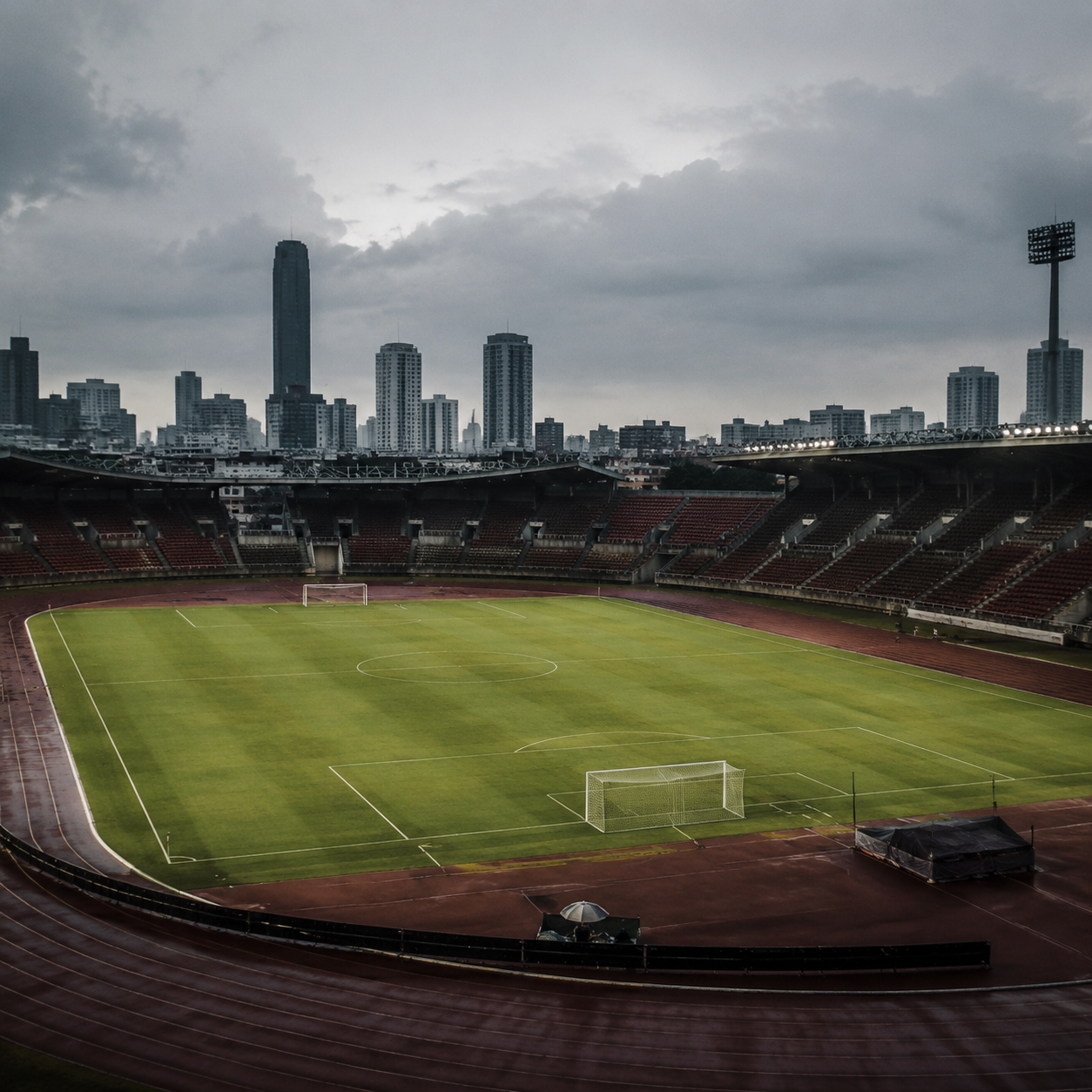 Empty football stadium during pandemic, empty grandstands, pristine pitch, overcast sky, atmospheric editorial photo