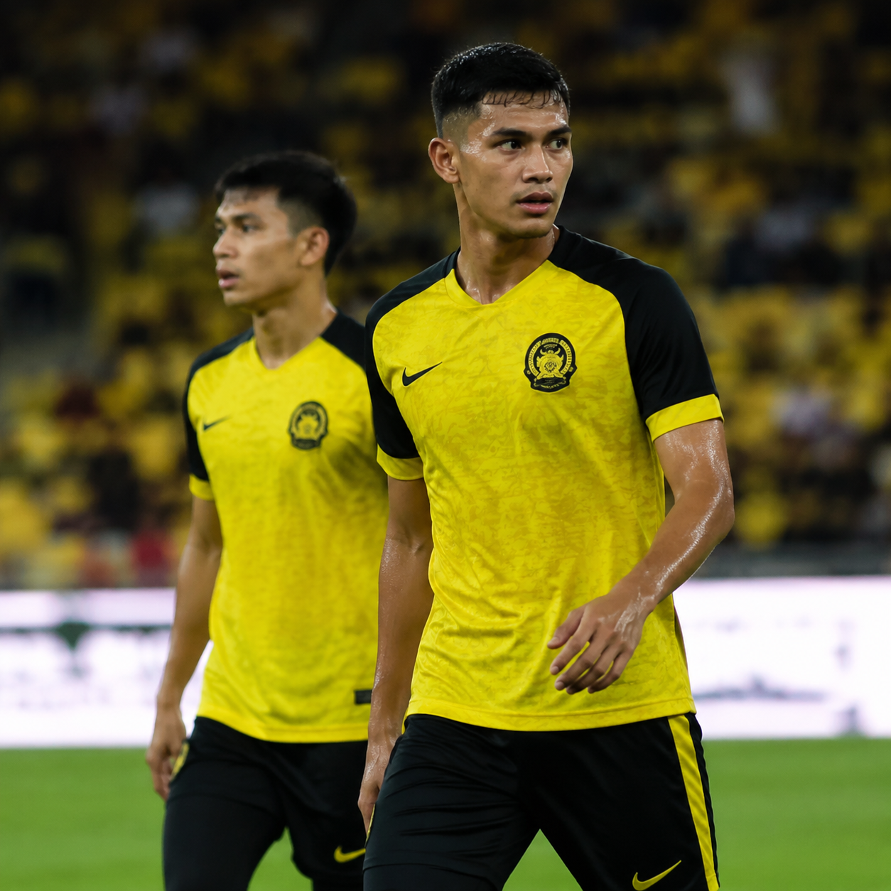Malaysian national football team players in yellow Harimau Malaya jerseys during match at Bukit Jalil stadium